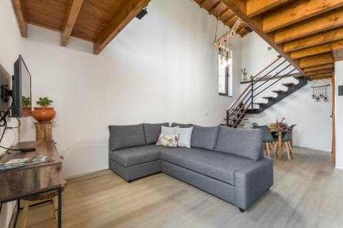 a living room with a gray couch and a staircase at Casas de Xisto in Raiva