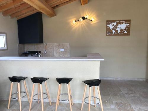 une cuisine avec un comptoir avec quatre tabourets de bar dans l'établissement Superbe villa neuve à 5 mn du centre, à Saint-Rémy-de-Provence