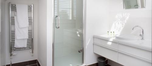 une salle de bain blanche avec une douche et un lavabo dans l'établissement Lakeside property with spa access on a nature reserve Owls Hoot HM69, à Somerford Keynes