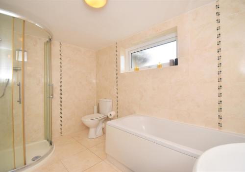 a bathroom with a tub and a toilet and a sink at Sagewood Cottage in Seaton