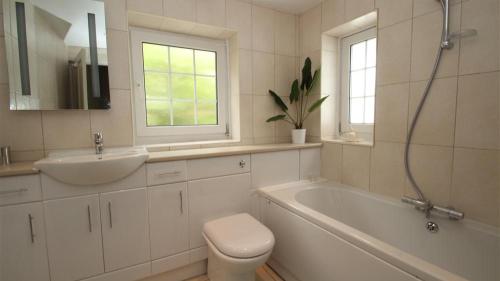 La salle de bains est pourvue d'un lavabo, d'une baignoire et de toilettes. dans l'établissement Cockleshell Cottage, à Mumbles
