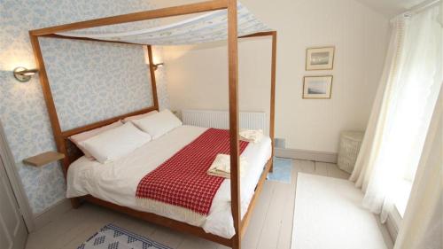 een slaapkamer met een hemelbed en een rode deken bij Cockleshell Cottage in The Mumbles