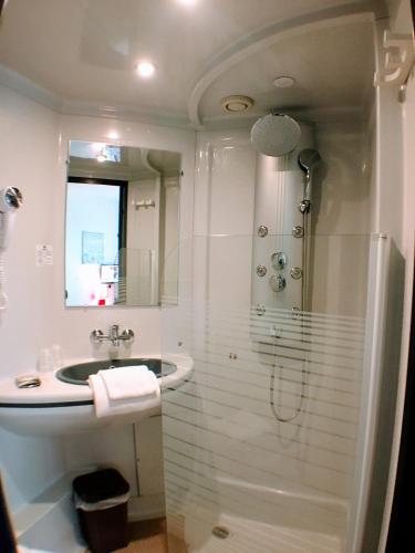 une salle de bain blanche avec un lavabo et une douche dans l'établissement L'Hôtel du Marais Romilly Centre, à Romilly-sur-Seine