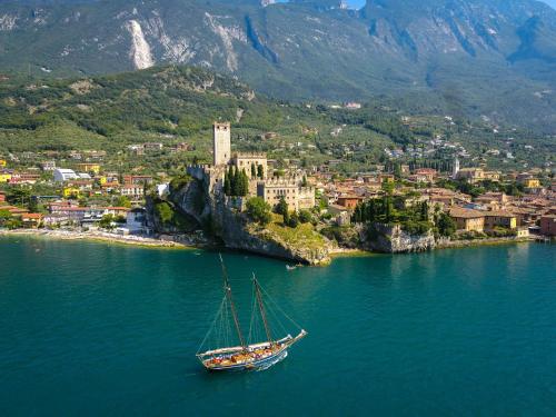 ein Boot im Wasser vor einer Stadt in der Unterkunft Gardesana Active Apartments in Malcesine