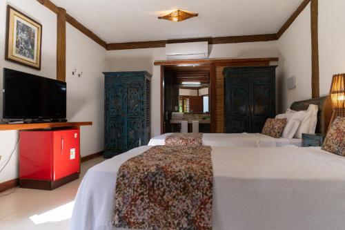 a bedroom with two beds and a flat screen tv at Hotel Villa Balidendê in Barra Grande