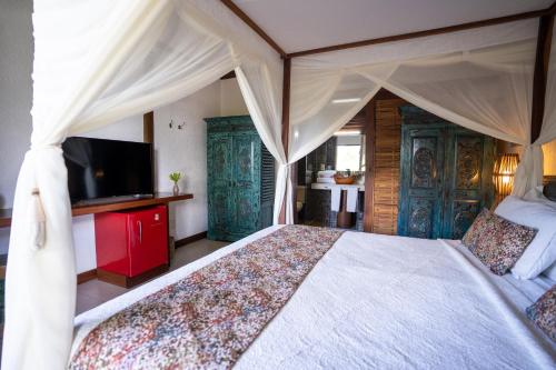 a bedroom with a large bed with a tv and a bed sqor at Hotel Villa Balidendê in Barra Grande
