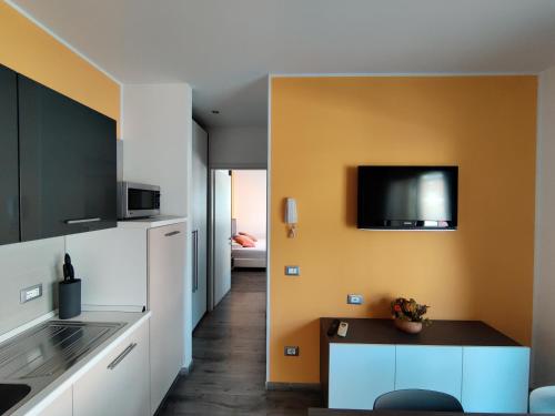 a kitchen with white cabinets and a tv on the wall at Gardesana Active Apartments in Malcesine