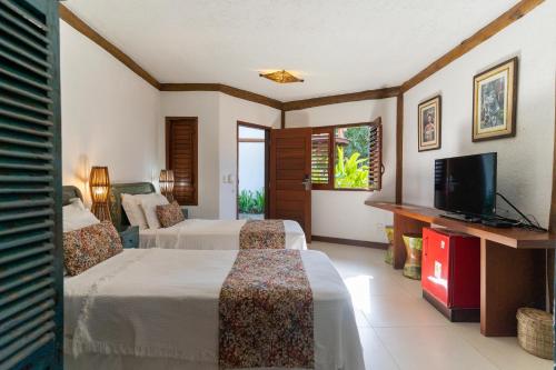 a hotel room with two beds and a flat screen tv at Hotel Villa Balidendê in Barra Grande