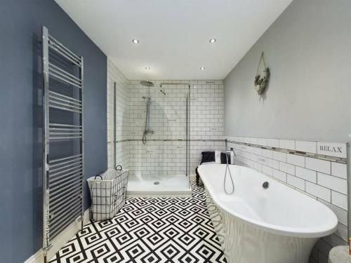 a bathroom with a bath tub and a shower at -- Huge -- 5-bedroom home & Private Gym by Tailored Accommodation in Swansea