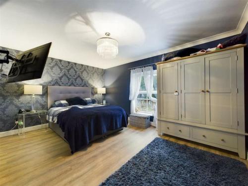 a bedroom with a bed and a cabinet and a rug at -- Huge -- 5-bedroom home & Private Gym by Tailored Accommodation in Swansea