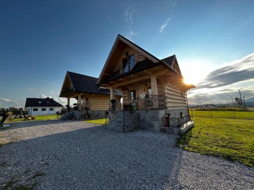 una cabaña de madera con la puesta de sol detrás de ella en Dziki Raj en Jabłonka