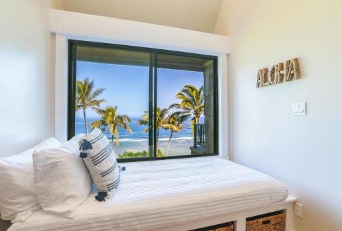 a bedroom with a window with a view of the beach at Sealodge J8 in Princeville