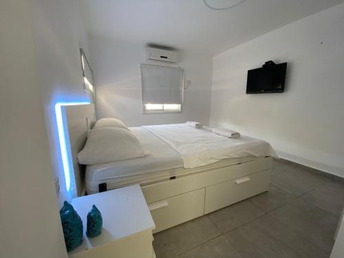 a bedroom with a bed with a tv on the wall at Romi's suite by LOREN VILLAGE in Neve Zohar