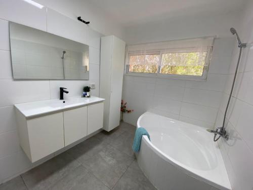 Baño blanco con bañera y lavamanos en Romi's suite by LOREN VILLAGE, en Neve Zohar