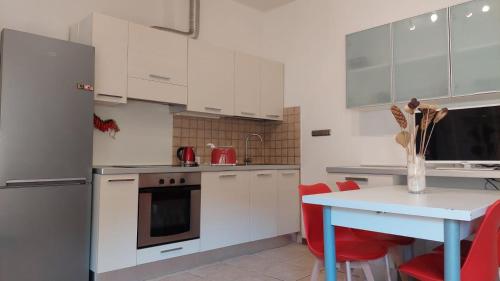 una cocina con armarios blancos y una mesa con sillas rojas en Casa Vacanze I Leoni Empoli, en Empoli