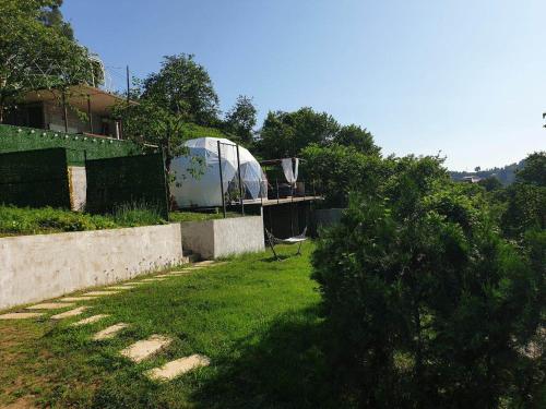 un jardín con invernadero en el fondo y un patio con césped en Annas Glamping, en Batumi