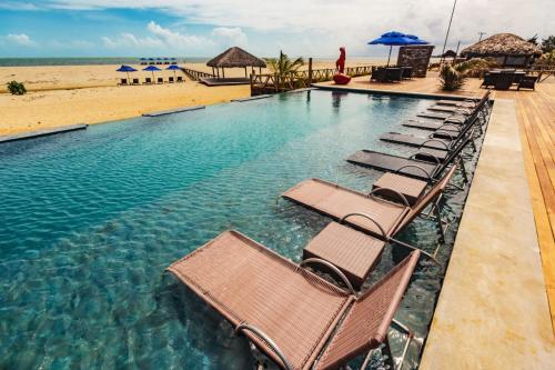 uma piscina com espreguiçadeiras e a praia em BobZ Boutique Resort, Suíte 21 em Barra Grande