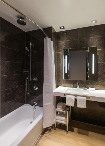 a bathroom with a tub and a sink and a mirror at AC Hotel Cincinnati at Liberty Center in West Chester