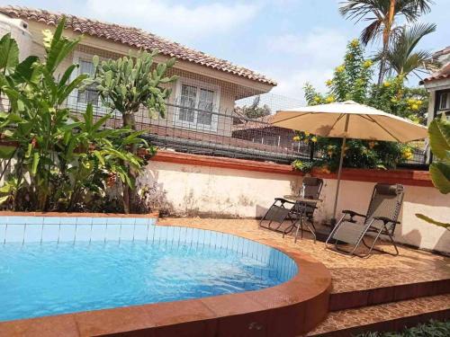 a swimming pool with an umbrella next to a house at Private Villa with Swimming Pool in Babakan Madang