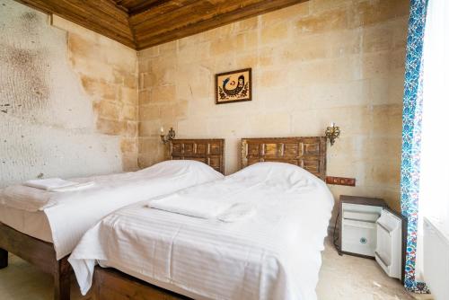 1 dormitorio con 1 cama con sábanas blancas en Cappadocia inans Cave & Swimming Pool Hot, en Nevşehir