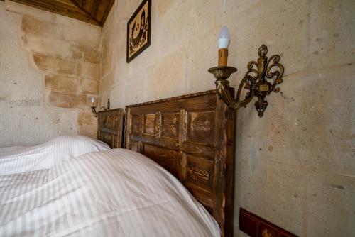 een slaapkamer met een bed met een houten hoofdeinde bij Cappadocia inans Cave & Swimming Pool Hot in Nevsehir