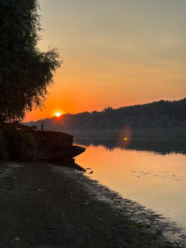 um pôr-do-sol sobre um corpo de água com uma doca em Kuca na Dunavu em Belgrado