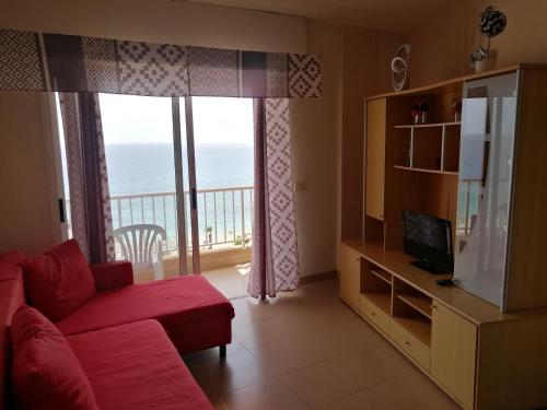 a living room with a couch and a television and a balcony at Apartamentos Vista Bahia in Los Cristianos