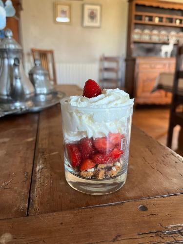 - un dessert avec des fraises et de la crème fouettée sur une table en bois dans l'établissement Oh ! Fleurs des champs, à Chaumont-sur-Tharonne