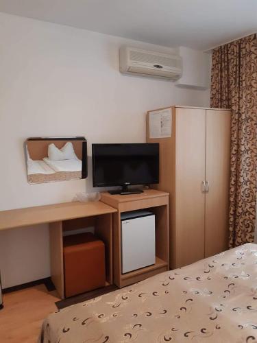 a room with a desk with a television and a bed at Hotel Mya in Bistriţa