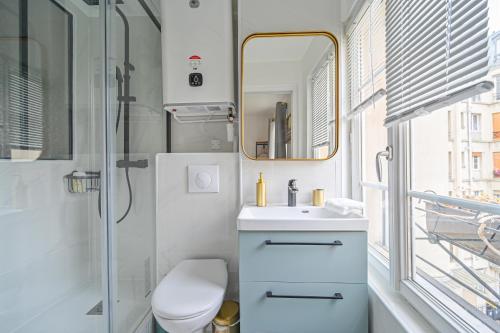 uma casa de banho com um WC, um lavatório e um espelho. em Studio Parisien - Quai Valmy em Paris