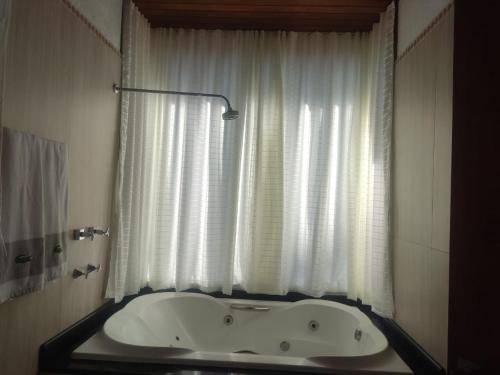 a bath tub in a bathroom with a window at Zatara's Lodge - Monte Verde MG in Camanducaia