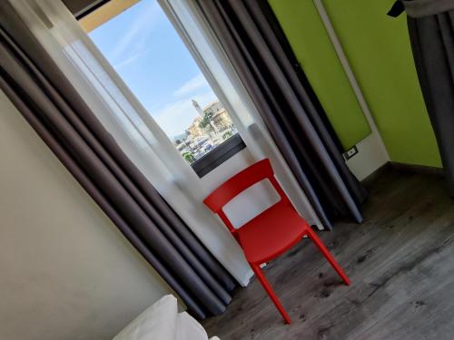 a red chair sitting in front of a window at Gardesana Active Apartments in Malcesine