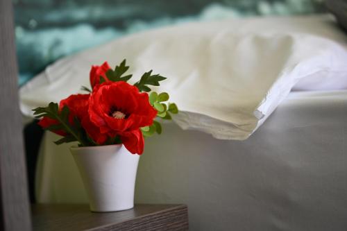 a vase with red flowers on a table next to a bed at Gardesana Active Apartments in Malcesine