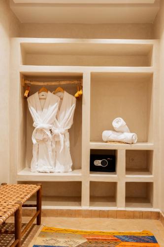 マラケシュにあるLe Palais Averroes - Adults Onlyの白い衣類を棚に掛けたウォークインクローゼット