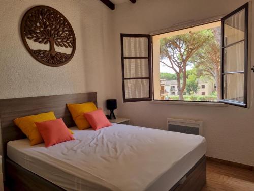 une chambre avec un lit avec des oreillers orange et jaunes dans l'établissement Le CASTILLON A 10, aux Issambres