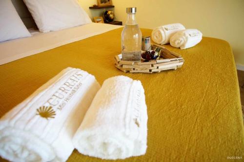 a bed with towels and a bottle on a table at Currais o pequeno paraíso entre o mar e a serra in Aveiro