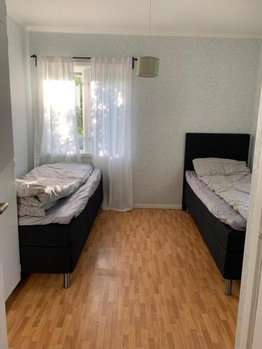 2 Betten in einem kleinen Zimmer mit Holzböden in der Unterkunft Lägenhet på Strömsholm in Jönköping