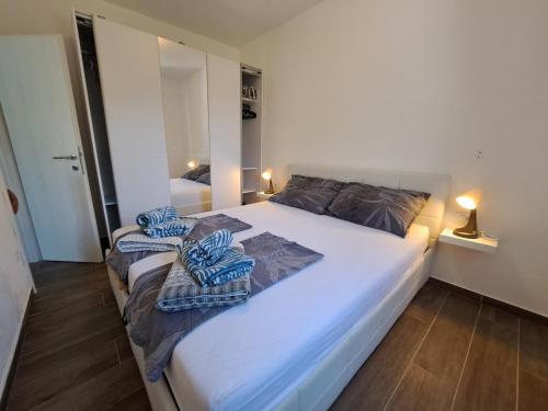 a bedroom with a large white bed with towels on it at Apartman Portorus in Lastovo