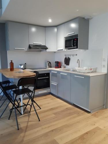 une cuisine avec des armoires blanches et une table et des chaises dans l'établissement Appart Cosy proche de La Rochelle, à Périgny