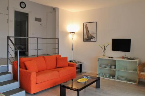 a living room with an orange couch and a television at Gardesana Active Apartments in Malcesine