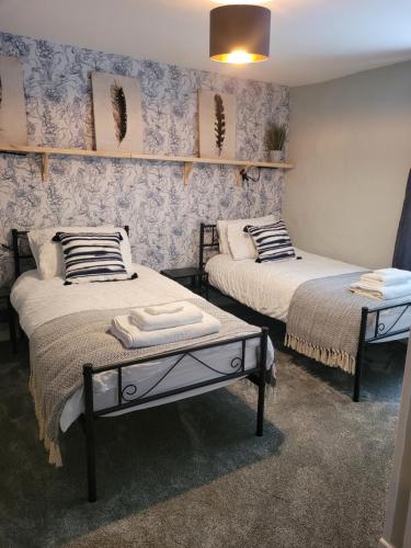 2 camas en una habitación con papel pintado azul en Ty Golchi - Cosy traditional cottage in Corris en Corris