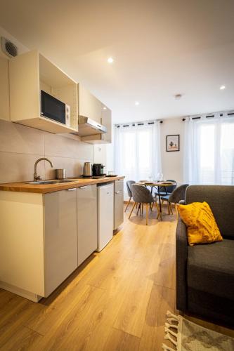 une cuisine et un salon avec un canapé et une table dans l'établissement L'Albatros 008 - Hypercentre Cosy Wifi, à Saint-Quentin