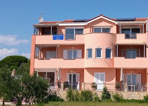 a pink building with a blue sign on it at Apartmani Brkic - Seaview apartments - Sand beach in Nin
