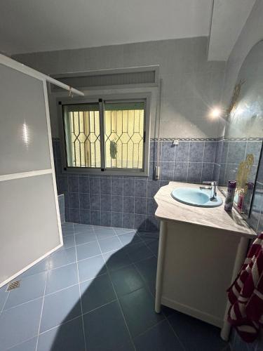a blue tiled bathroom with a sink and a window at Sfiha/Hoceima huis in Al Hoceïma