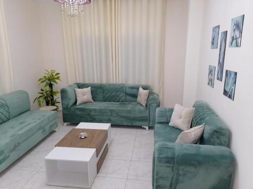 a living room with two green couches and a coffee table at Yaso Roof & Apartments in Amman