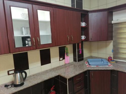 a kitchen with wooden cabinets and a counter top at Yaso Roof & Apartments in Amman