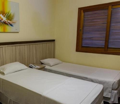 two twin beds in a room with a window at Hotel Brisa do Japi in Cabreúva