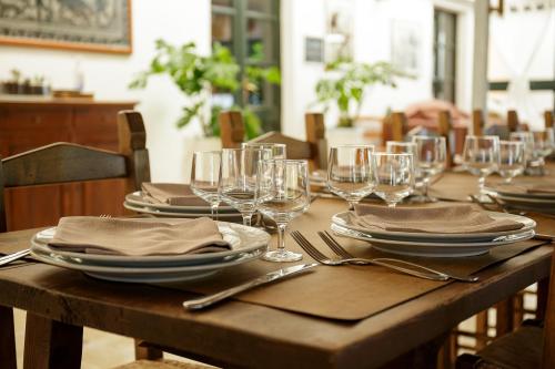 a wooden table with plates and wine glasses on it at Hotel Sa Pedrera in Càbras