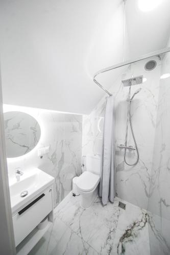 a white bathroom with a toilet and a sink at Apartamentai Ieva Kunigiškėse in Palanga