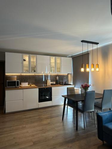 uma cozinha com armários brancos e uma mesa com cadeiras em Torņa apartamenti em Roja